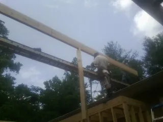 Carpenter setting a ridge beam over a new addition frame — Ice Dam Removal by Roofing Brothers in Chincoteague Island