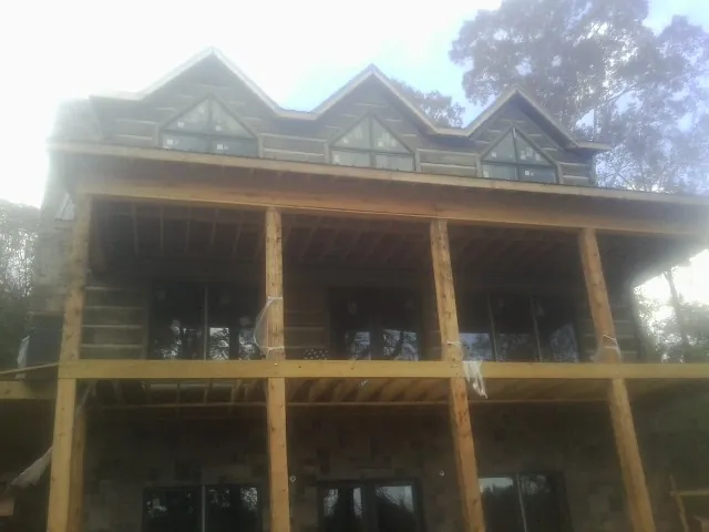 Dormers and porch framing on a large log home under construction — Roof Coating work by our crew in Chincoteague Island