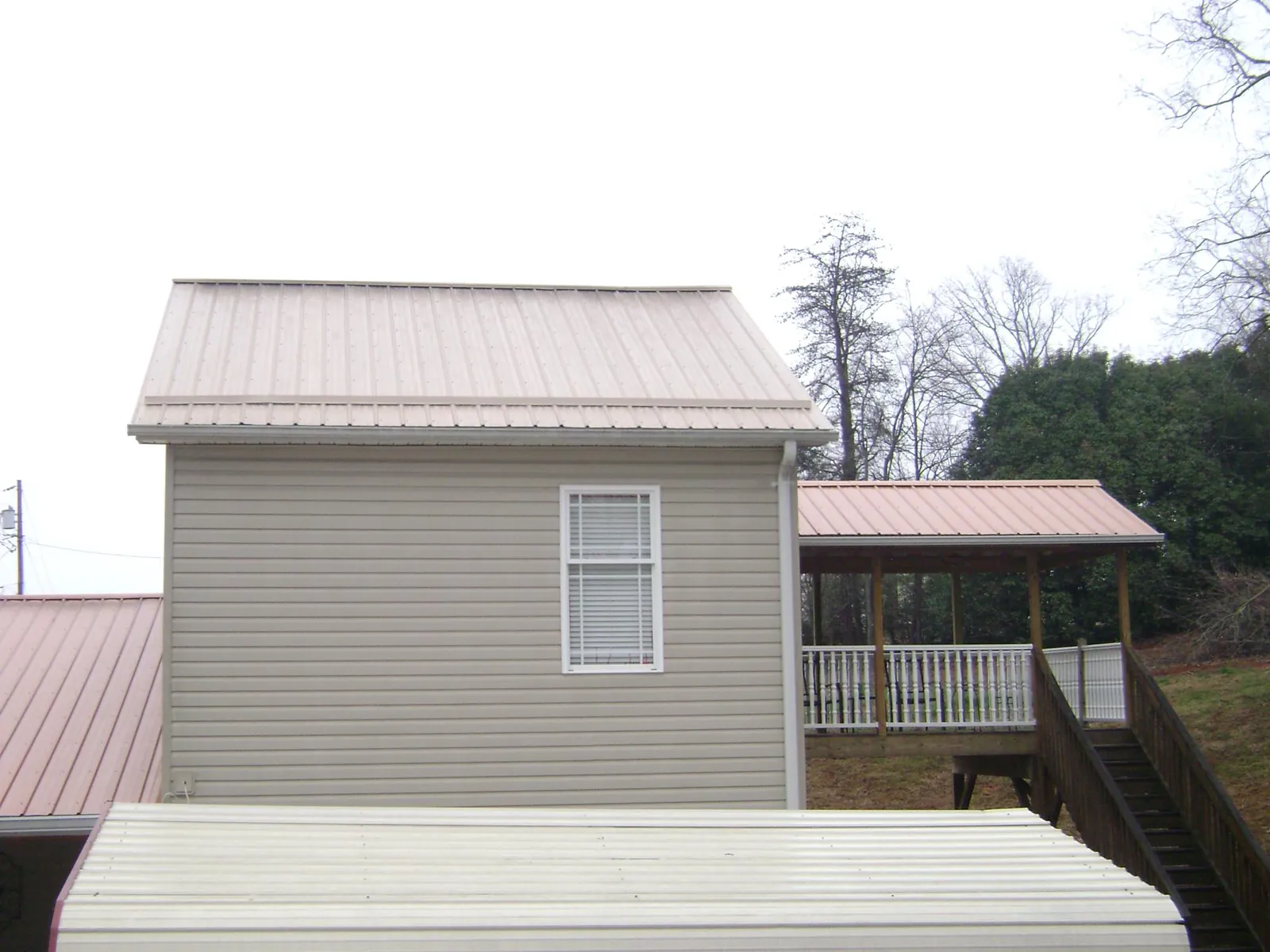 Tan metal roofs on a two story addition and attached porch, from a Roof Replacement job in Chincoteague Island