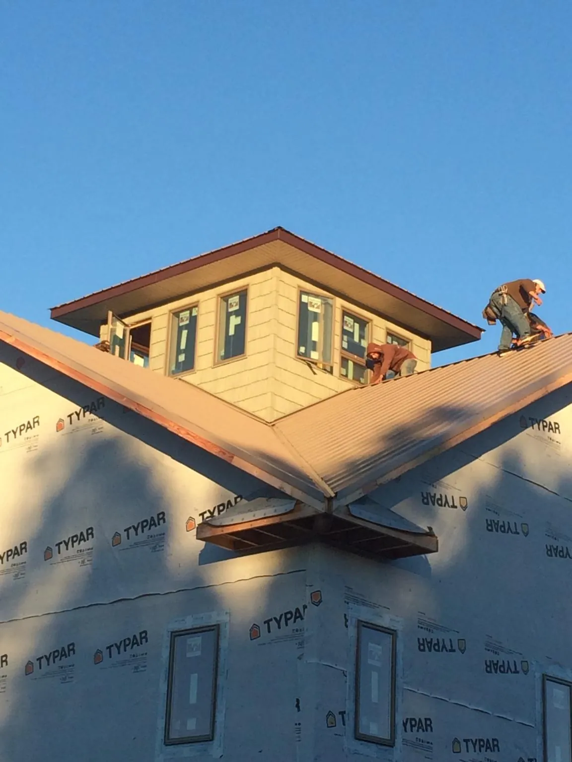 Roofers working around a rooftop cupola on a new metal roof at sunset — Roof Waterproofing in Chincoteague Island by Roofing Brothers